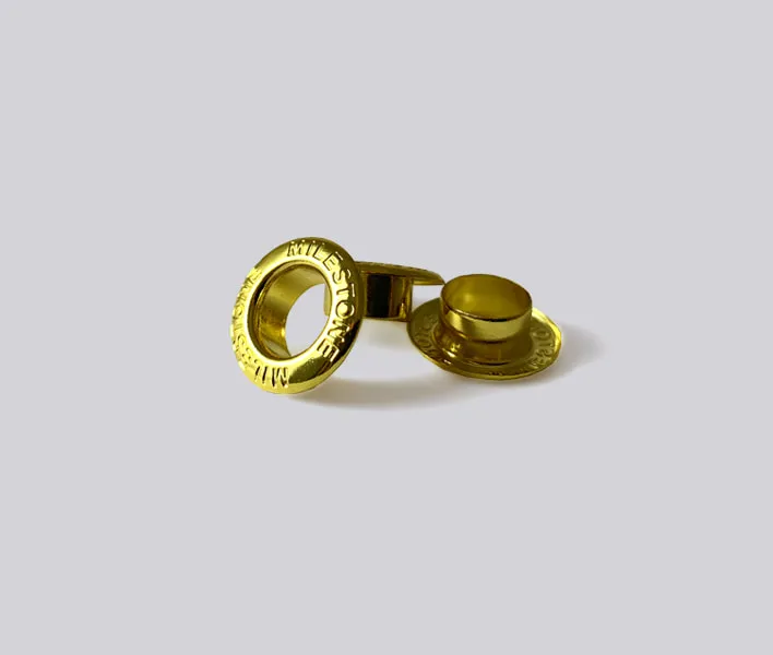 Gold engraved metal clothing eyelet.